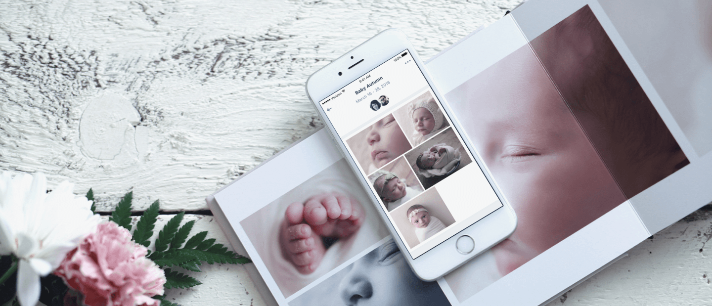 Mobile device showing an album of a baby on the amazon photos app, placed on a physical photo album of the baby